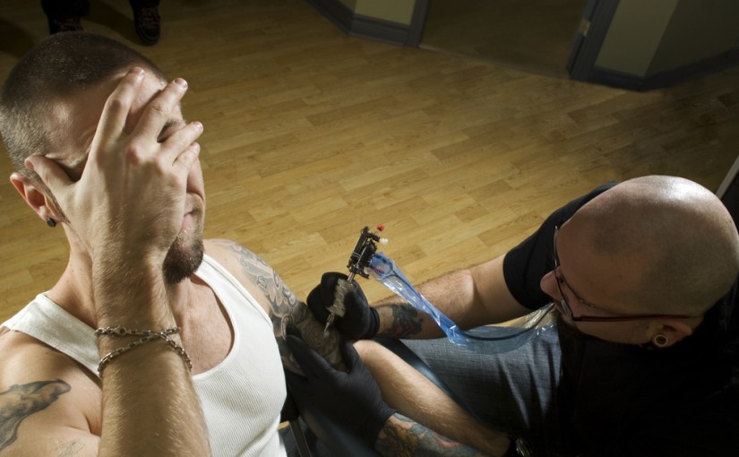 Client in pain getting a tattoo by concentrated tattooer